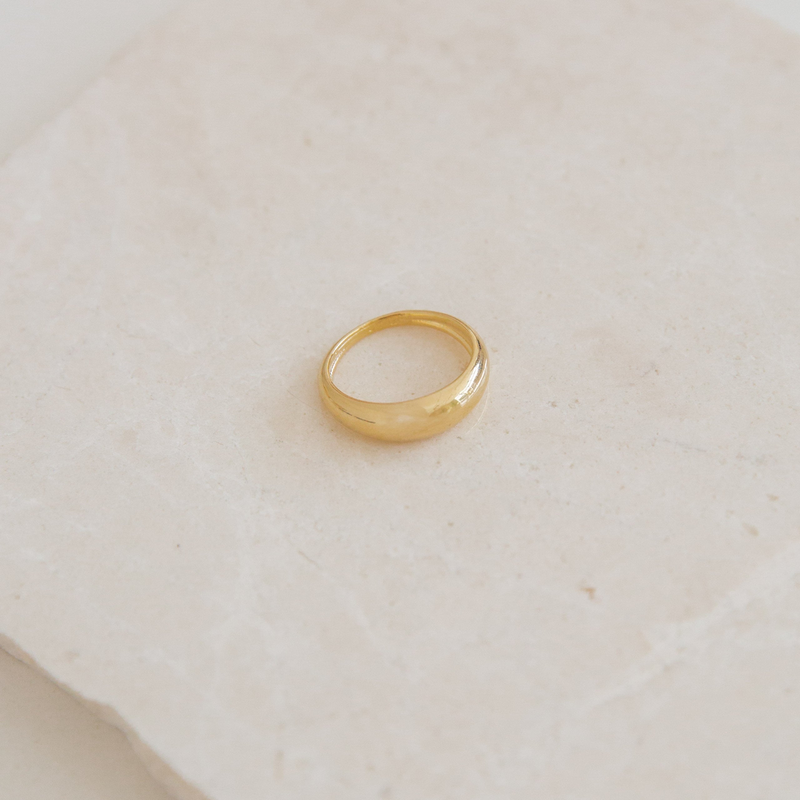 Gold ring on a light beige surface