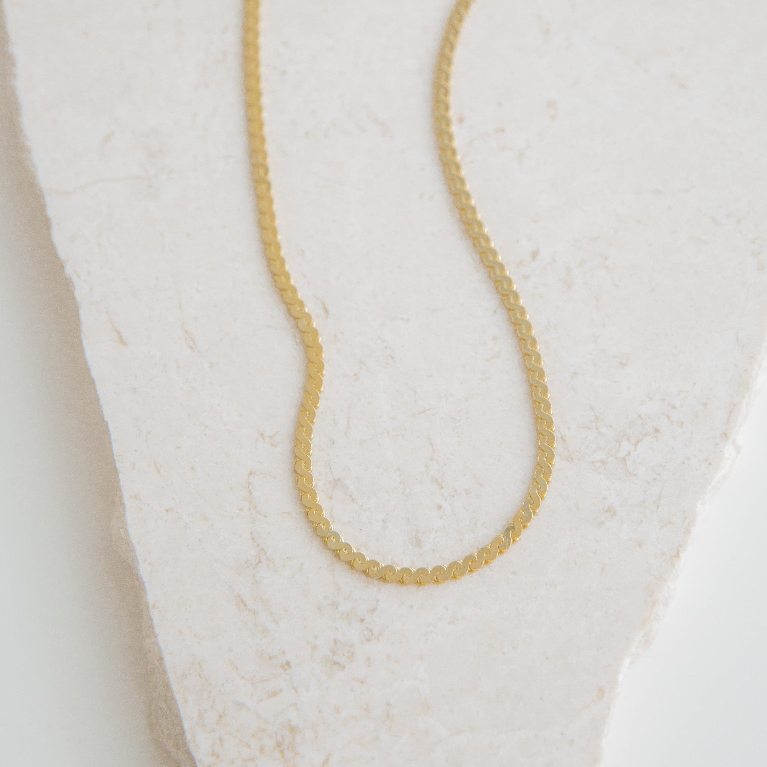 Gold necklace on a textured white surface