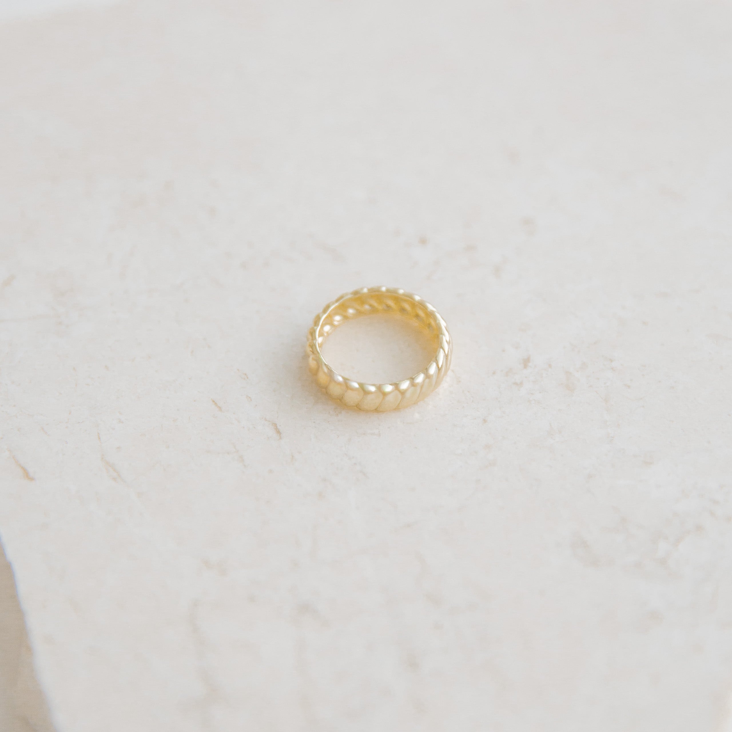Gold ring on a light beige surface