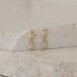 Gold earrings with clear stones on a stone surface