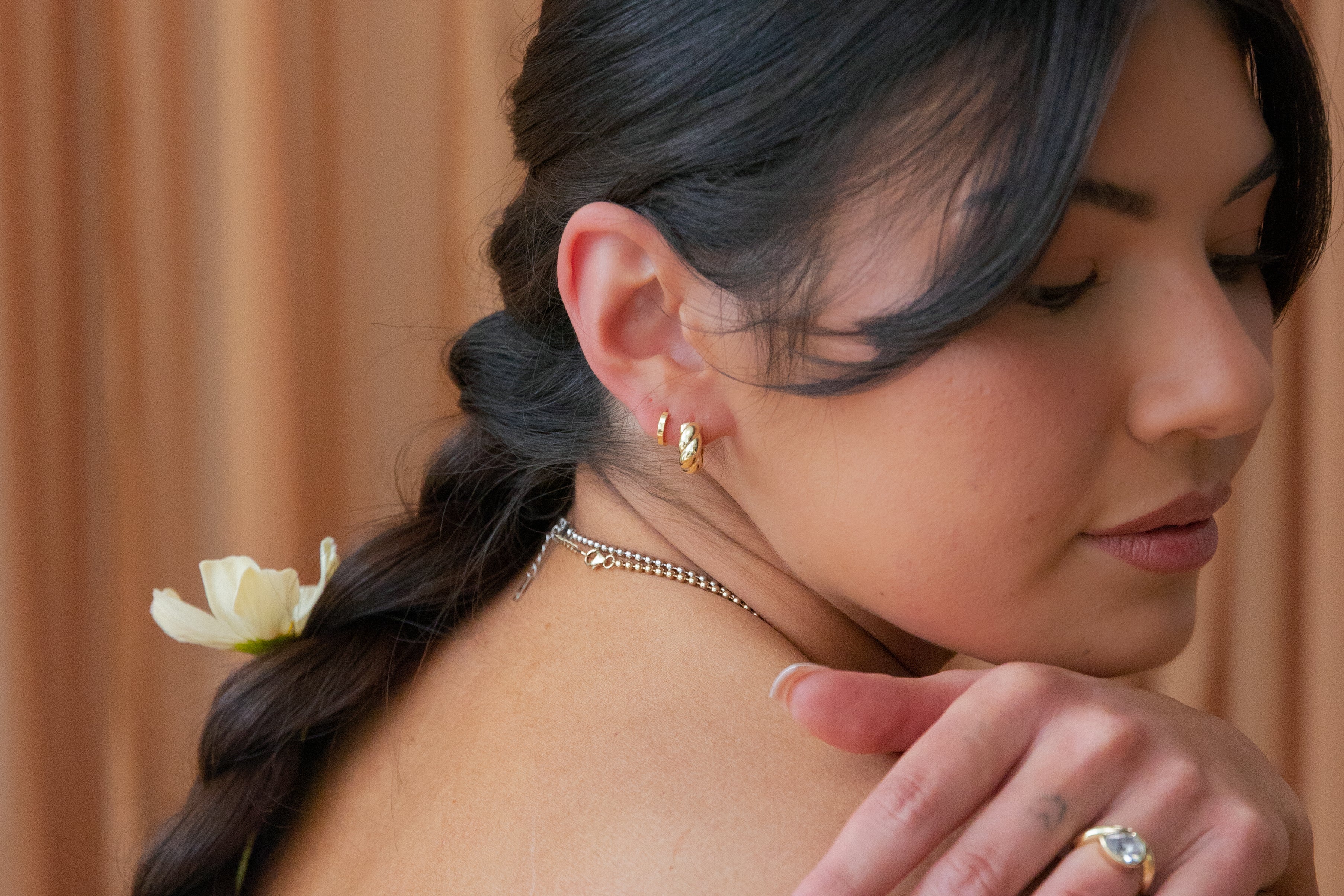 Woman with braided hair and floral accessory against a brown background