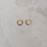 Gold hoop earrings on a textured beige surface