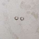 Two gold hoop earrings on a marble surface