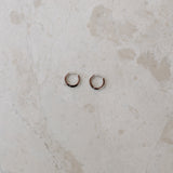 Two gold hoop earrings on a marble surface