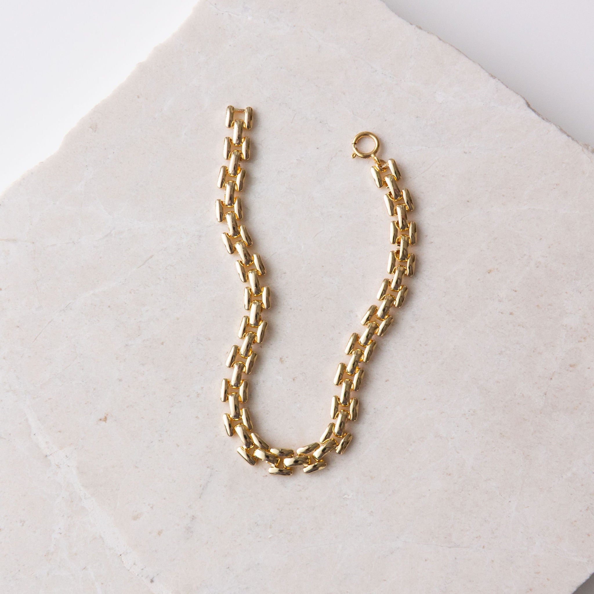 Gold Chain Bracelet on a textured beige surface