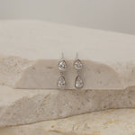 Pair of silver teardrop earrings on a marble surface