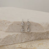 Pair of silver teardrop earrings on a marble surface