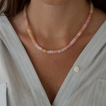 Necklace with pink and white beads worn by a person against a softly blurred background.