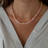 Necklace with pink and white beads worn by a person against a softly blurred background.