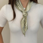 Woman wearing a green and white patterned hair tie on a white background