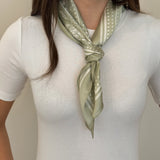 Woman wearing a green and white patterned hair tie on a white background