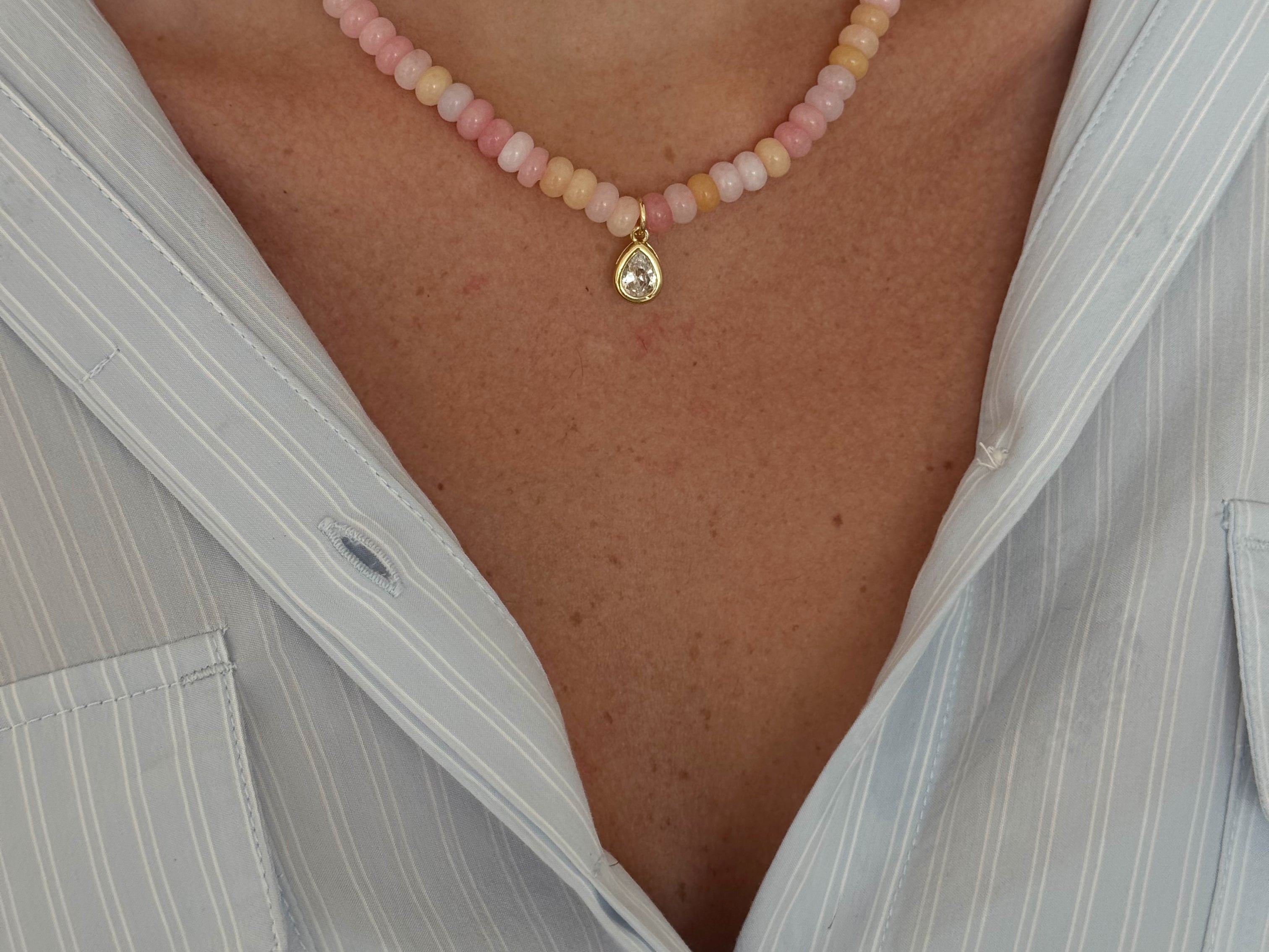 Close-up of a person wearing a pink beaded anklet with a gold charm.